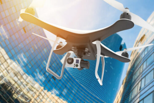 Drone with digital camera flying in a modern city at sunset: 3D rendering